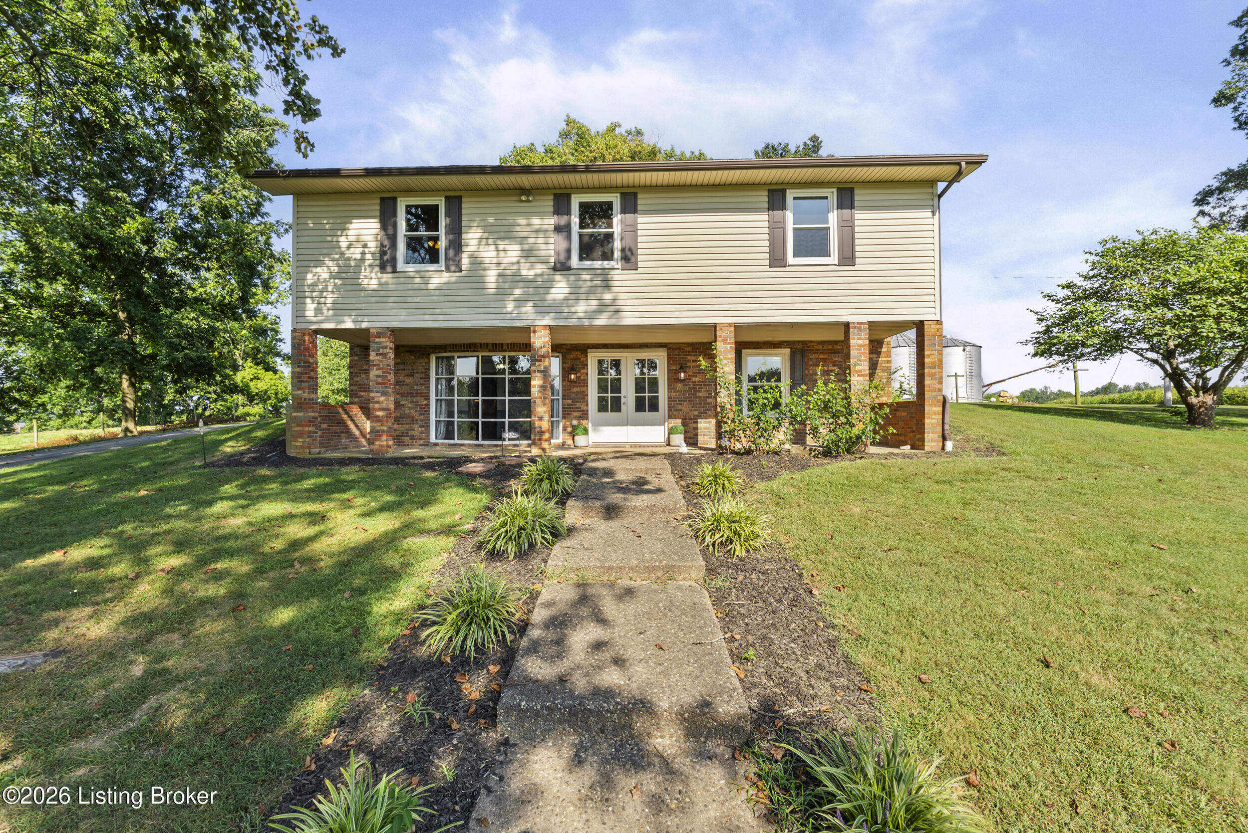 Raised two-story home with brick lower level, light siding, and a front walkway.