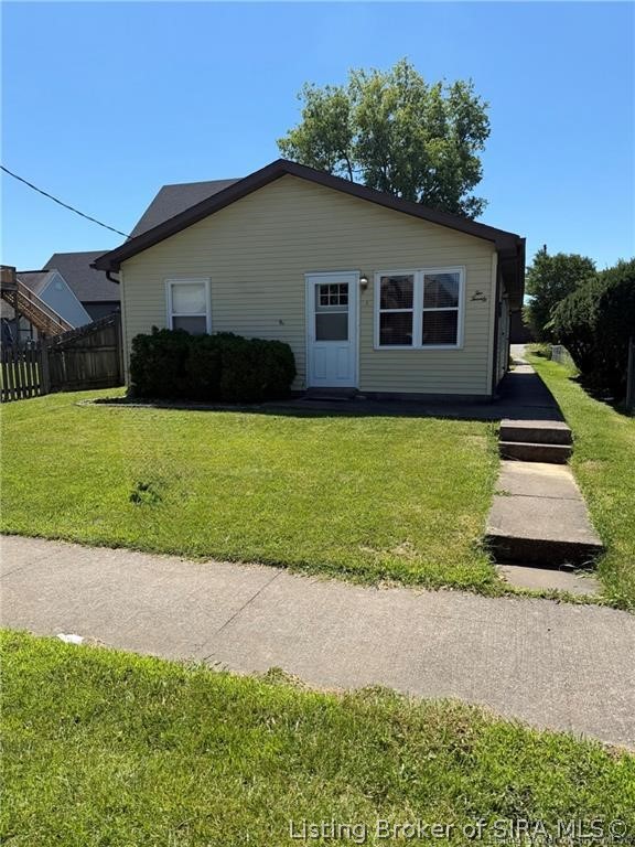 Single-story home with light siding, a front lawn, and a concrete walkway.