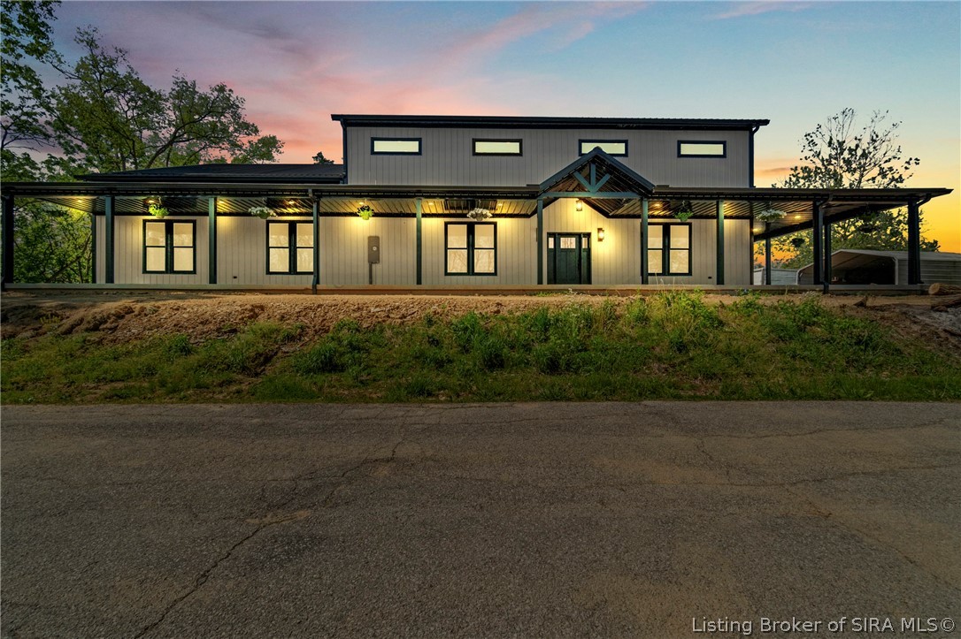 Modern gray home with a long covered porch and glowing lights at dusk.