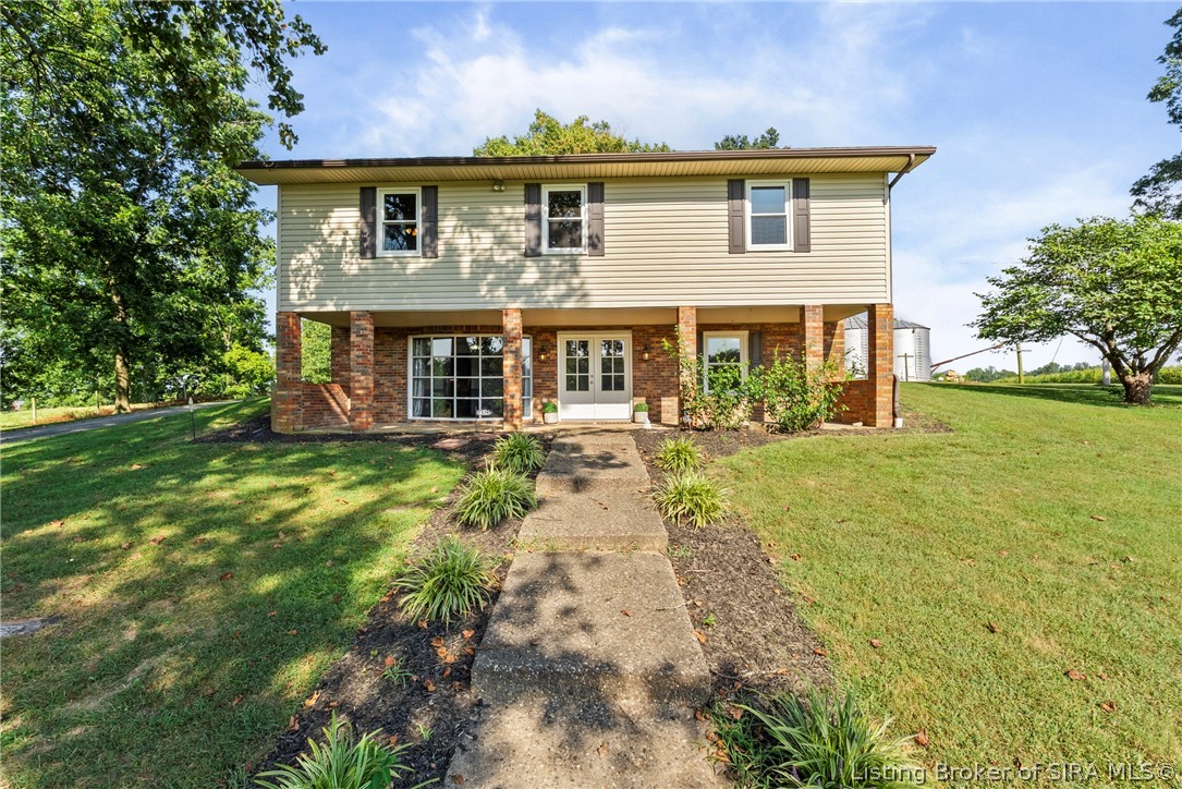 Two-story brick and cream-sided home with a concrete walkway and broad green lawn.