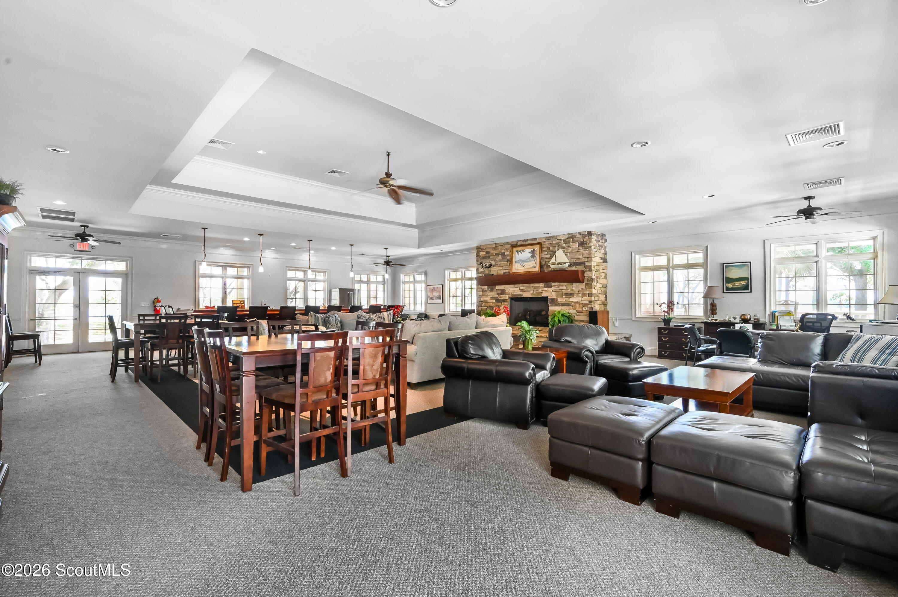 Furnished lounge and dining area with leather seating and a stone fireplace.