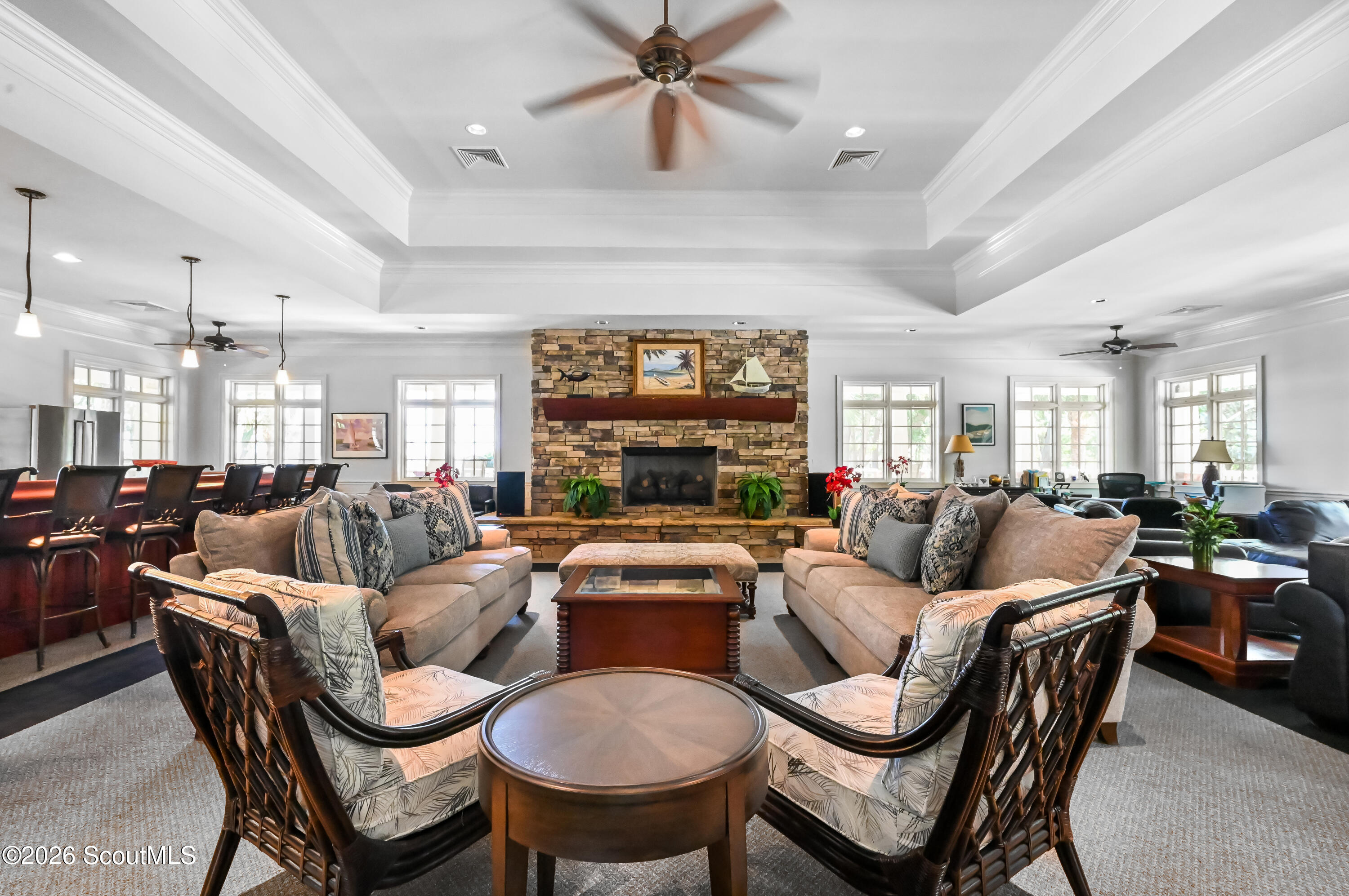 Furnished lounge with a large stone fireplace, surrounding sofas, and windows along both sides.