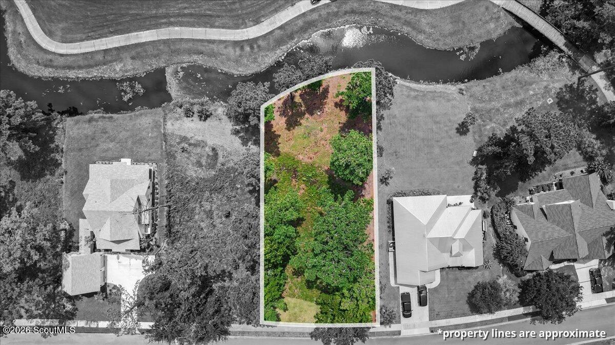 Vacant wooded lot outlined from the street to a waterway, with neighboring homes on either side.