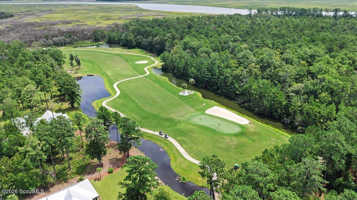 Aerial golf course with winding paths, ponds, sand bunkers, and surrounding woodland.