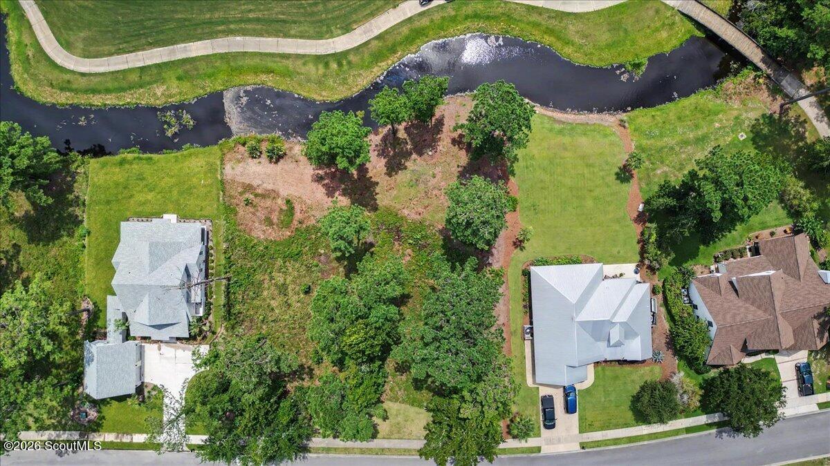 Aerial view of a vacant lot beside a creek, between neighboring homes.