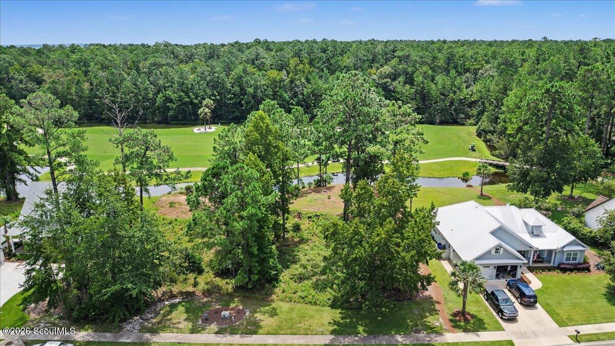 Wooded vacant lot beside a home, overlooking a manicured golf course and water feature.