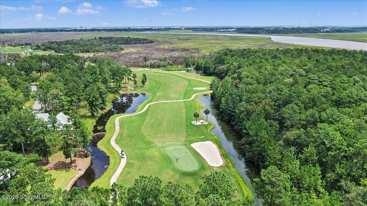 Aerial view of a golf course fairway bordered by ponds, woods, and coastal marshland.
