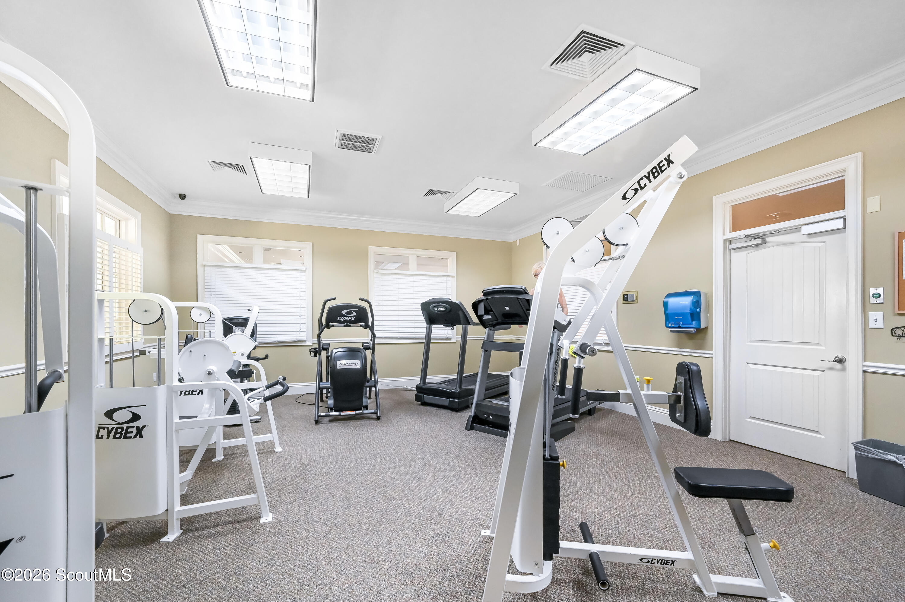Fitness room with Cybex exercise machines, treadmills, and windows with blinds.
