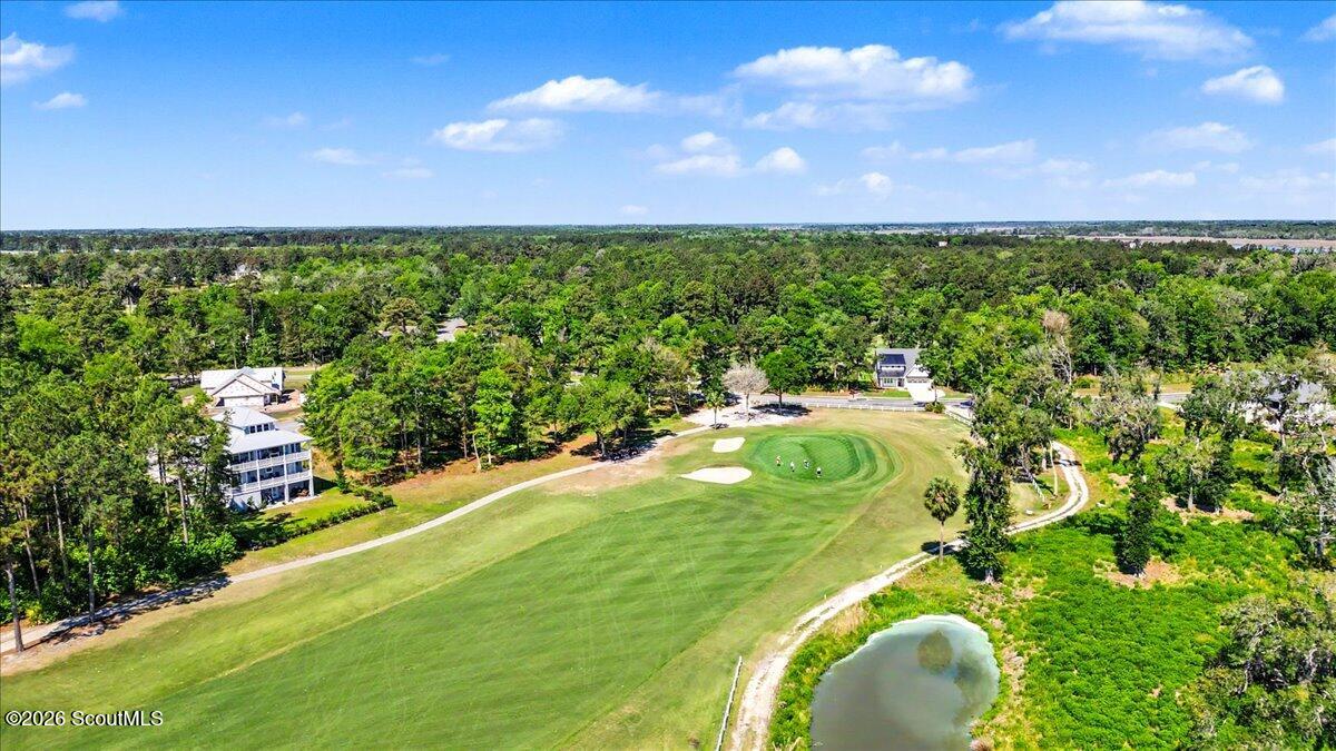 Aerial golf course with sand bunkers, a pond, and homes among the trees.