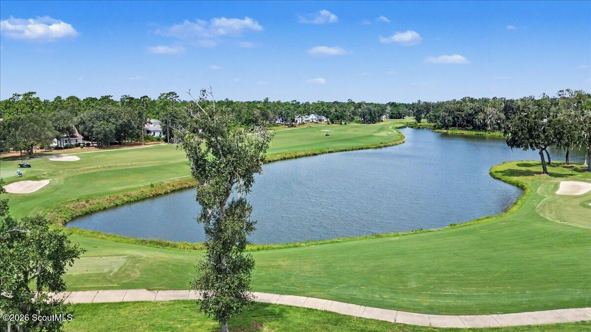 Golf course fairways curve around a pond, with homes and mature trees in the distance.
