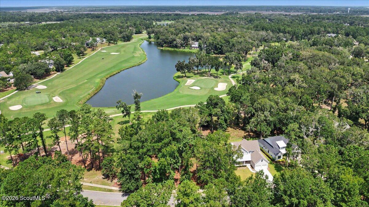 Aerial view of a wooded neighborhood, golf greens, sand bunkers, and a pond.