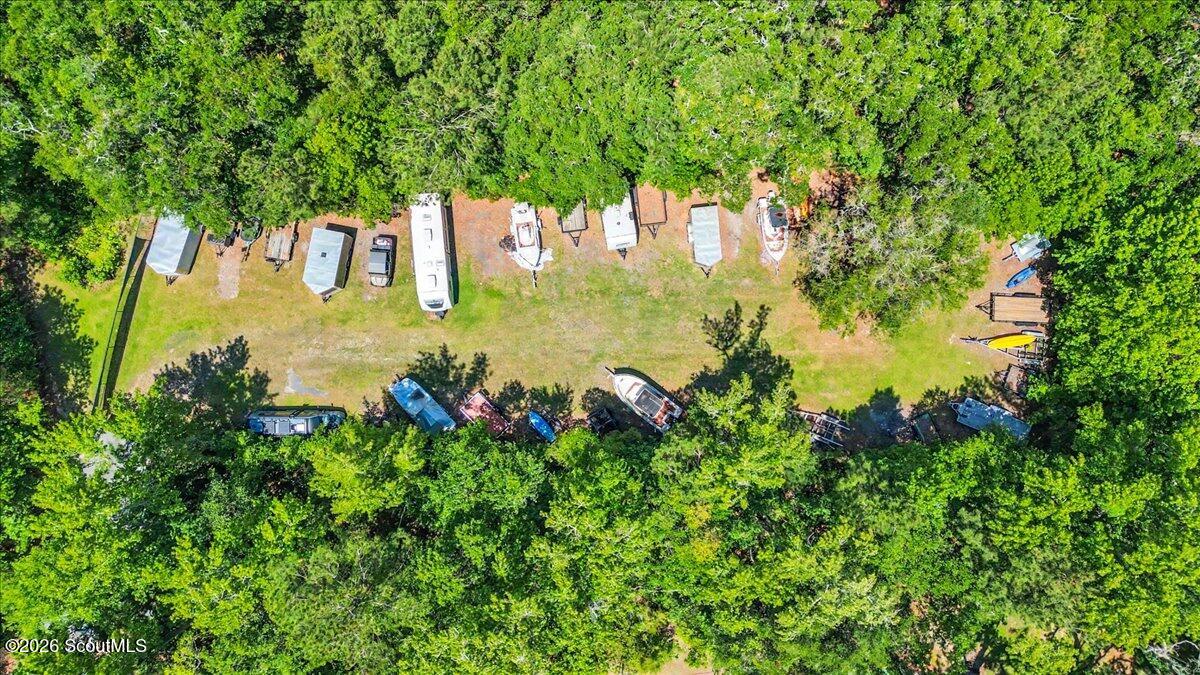Aerial view of a wooded lot with a long clearing and parked boats and trailers.