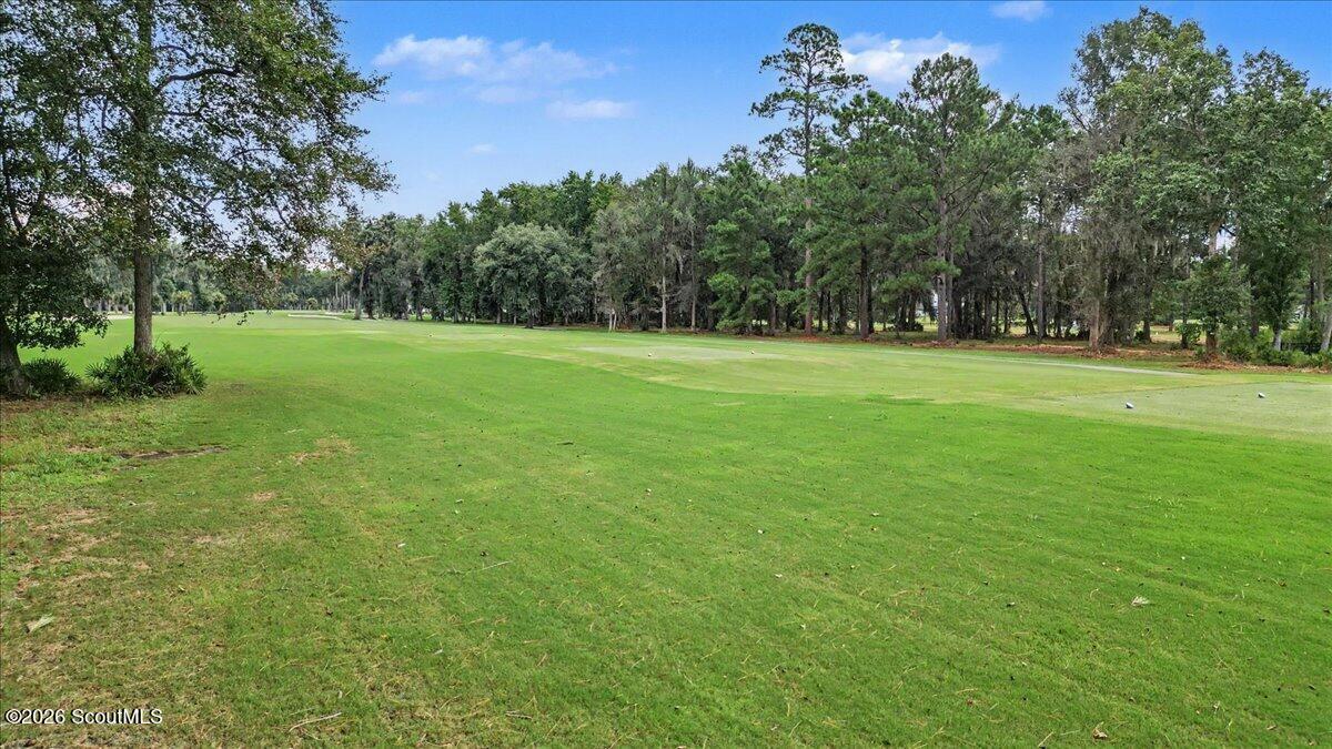 Manicured golf course fairway bordered by mature trees.