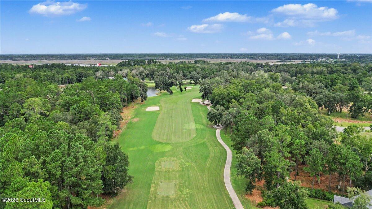Aerial view of a golf course fairway winding through wooded grounds with sand bunkers.