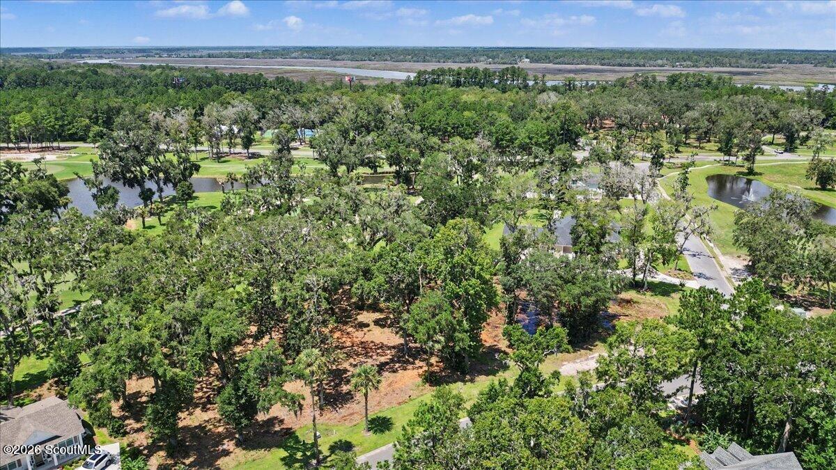 Aerial view of a wooded lot with a clearing, nearby ponds, and wetlands on the horizon.