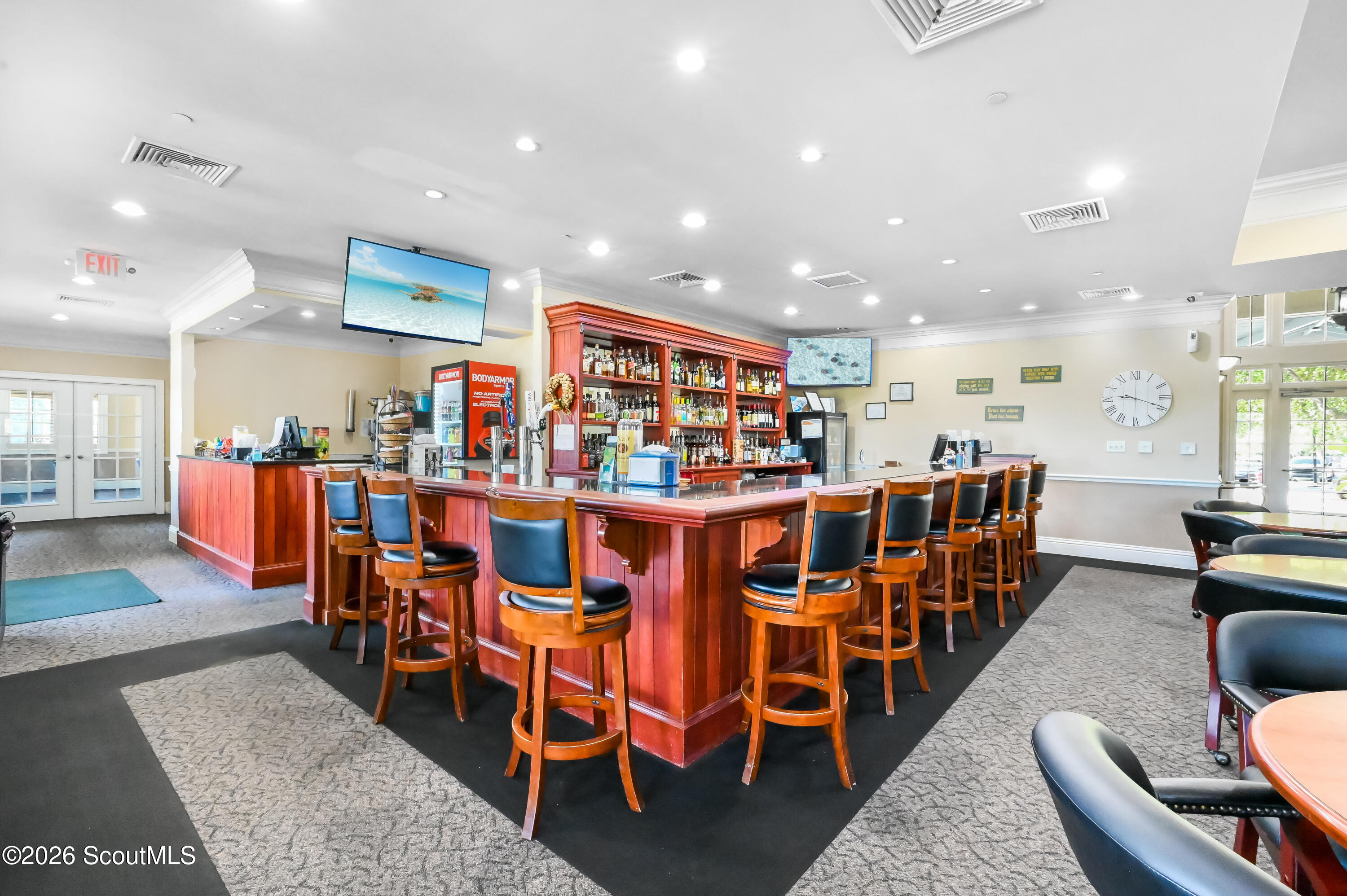 Bar lounge with a red wood counter, liquor shelves, and rows of bar stools.