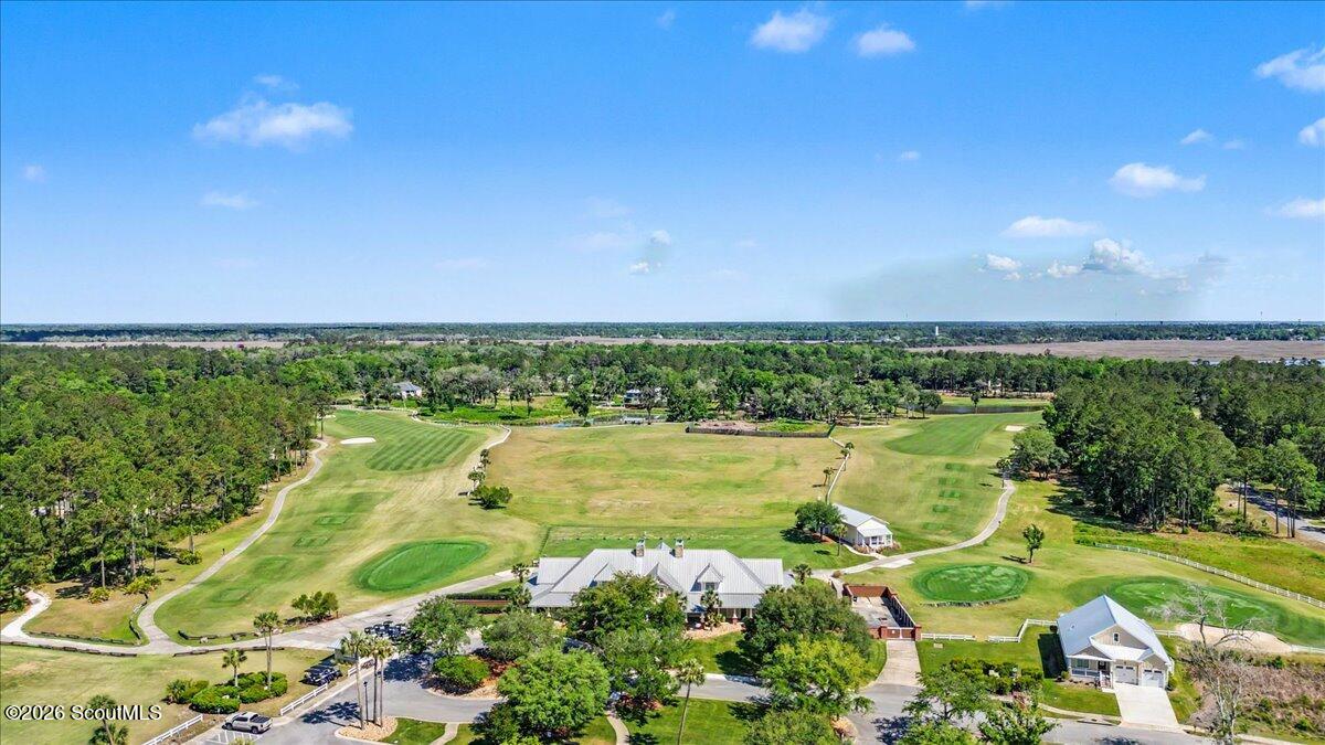 Aerial view of a golf course with manicured greens, fairways, and buildings.