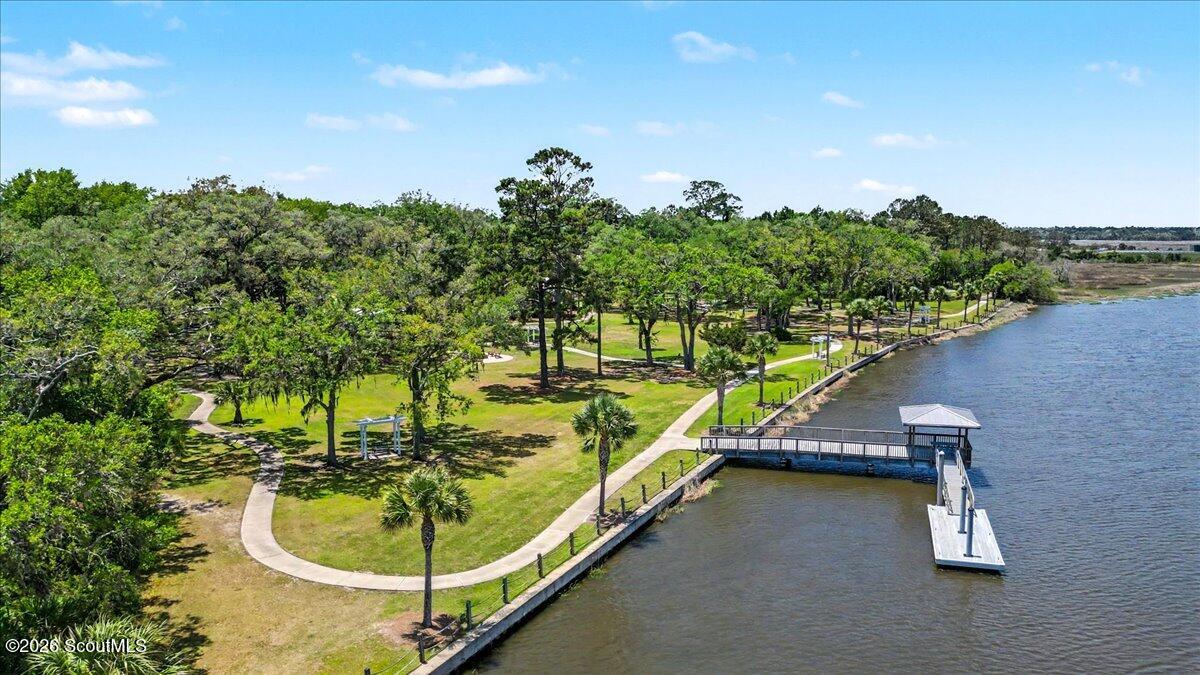Aerial view of a waterfront park with a dock, winding paths, and mature trees.