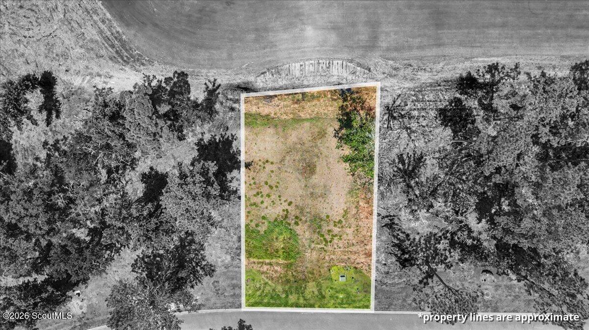 Aerial view of a cleared rectangular lot outlined among wooded land.