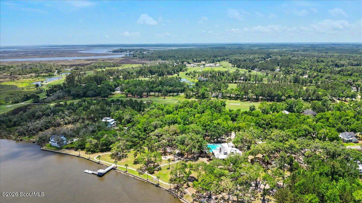Aerial view of a waterfront neighborhood, golf course, wooded homes, and coastal marshland.