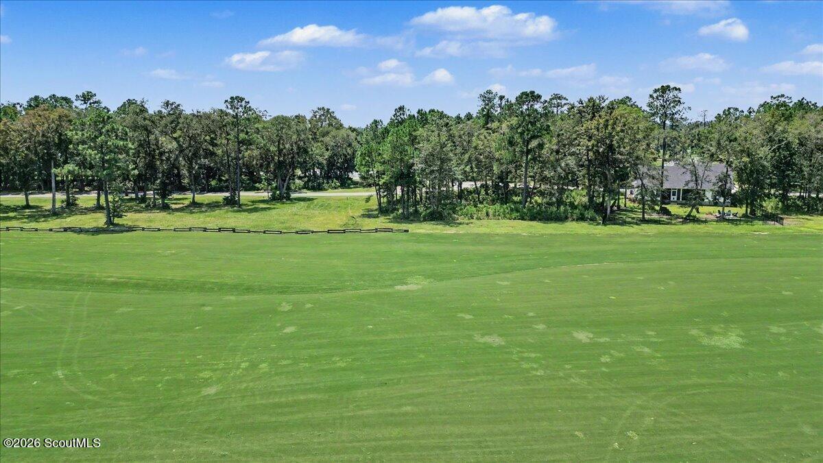 Golf course beside a wooded lot, with a neighboring house at the tree line.