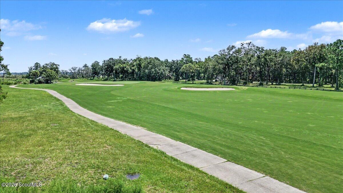 Golf course with two sand bunkers, a curving cart path, and a tree line.