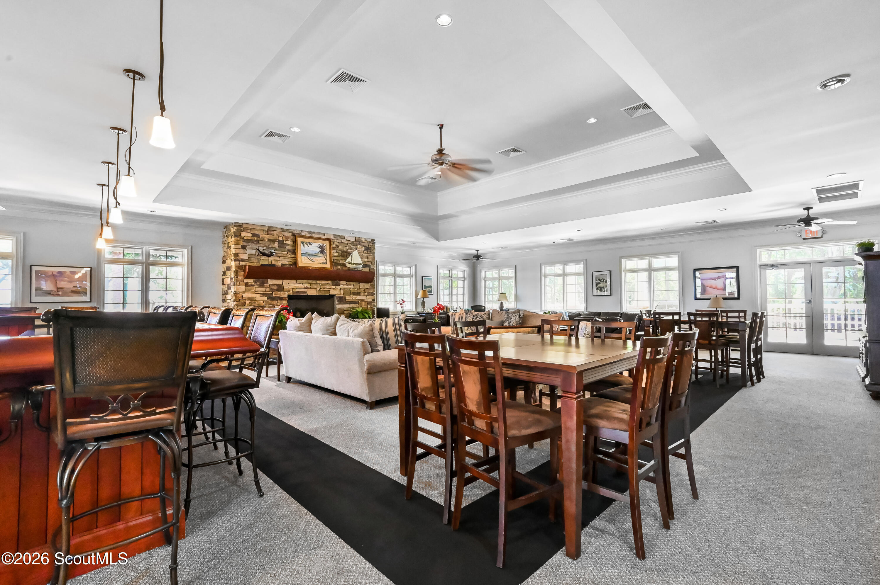Community room with stone fireplace, bar counter, and dining tables.