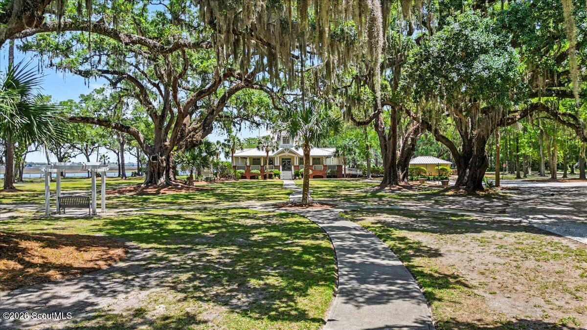 Oak-shaded grounds with a porch-front building, curved walkway, and water visible through the trees.