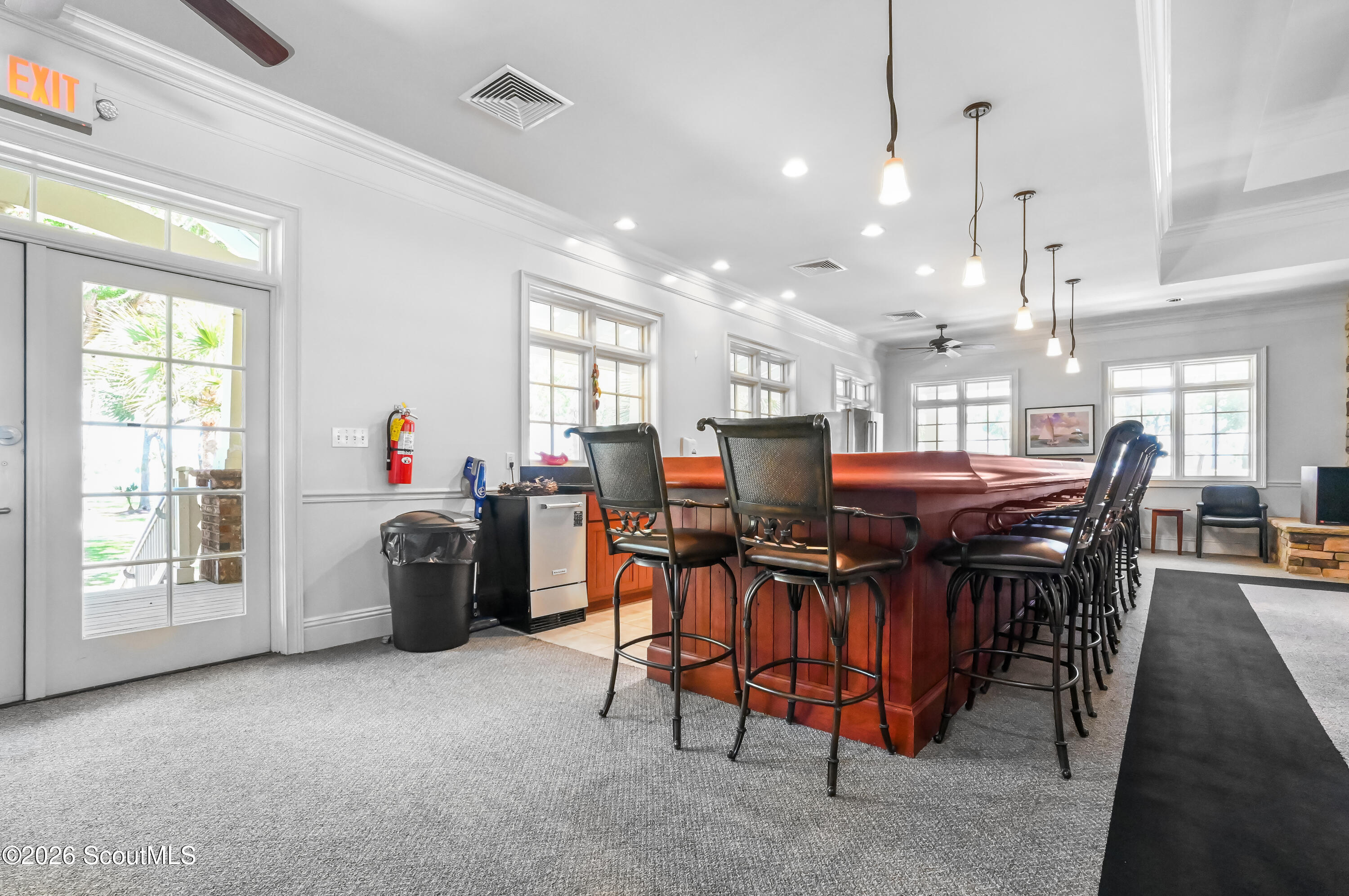 Community gathering room with a long red bar and rows of black stools.