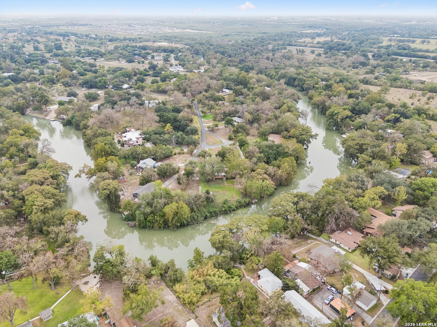 Aerial view of homes among trees along a winding river.