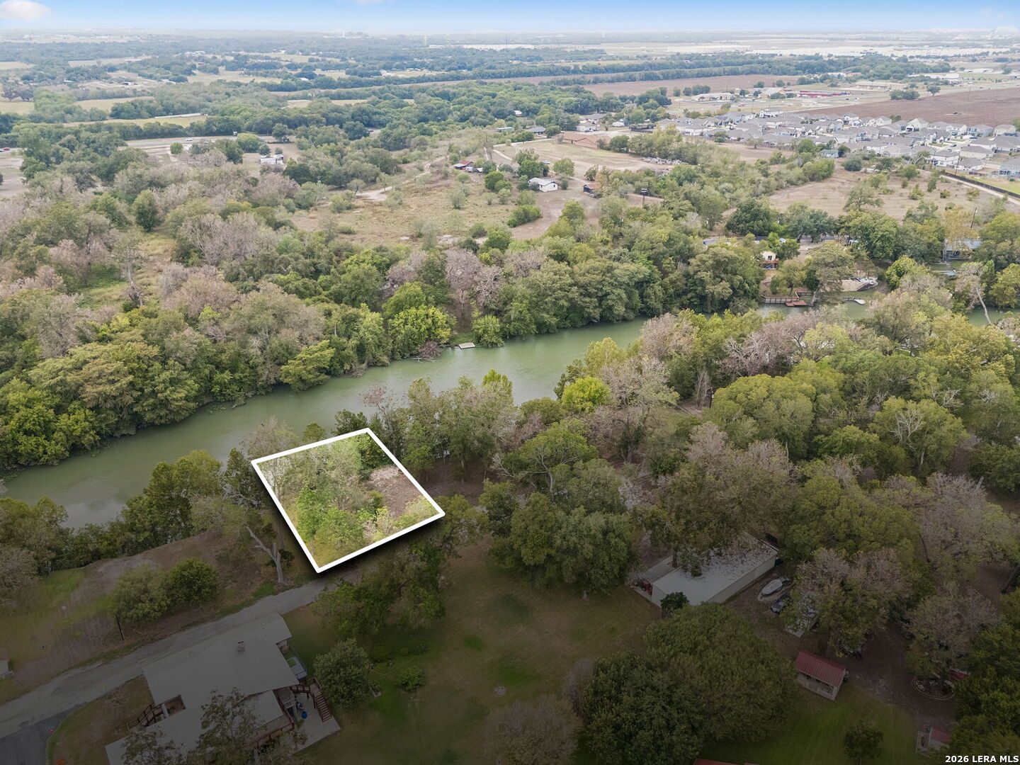 White outline marks a wooded riverside lot among mature trees.