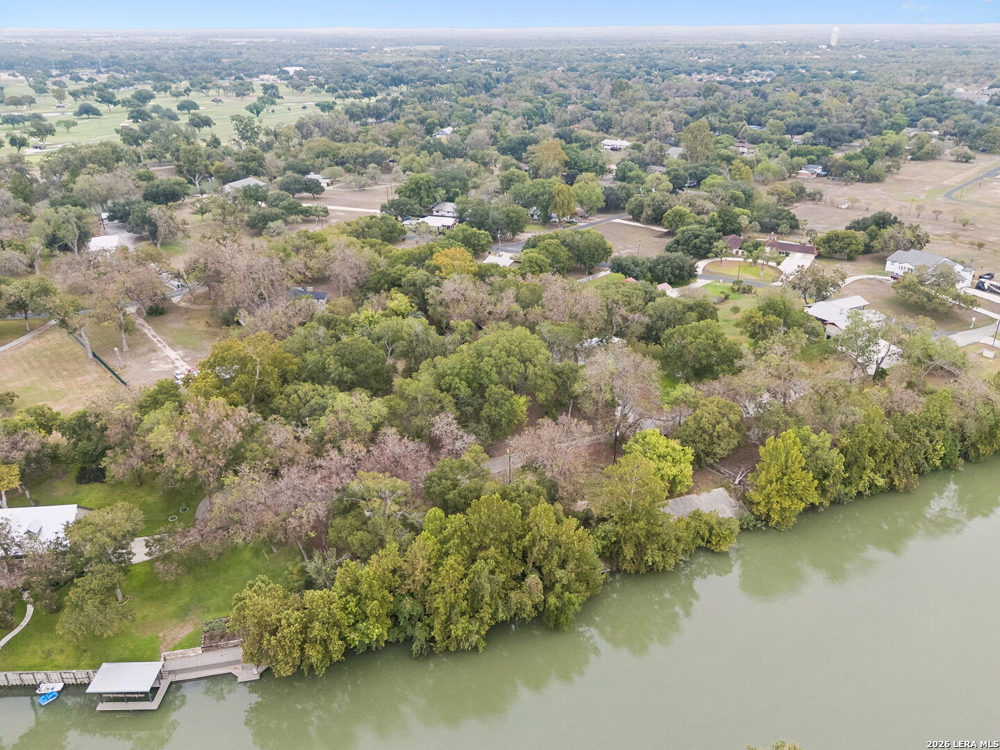 Aerial view of a wooded shoreline with homes and docks beside the water.