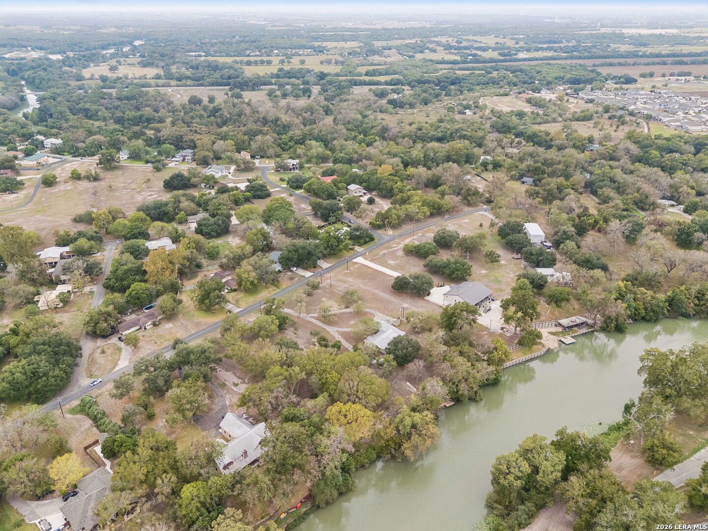 Aerial view of homes and wooded lots along a winding river.