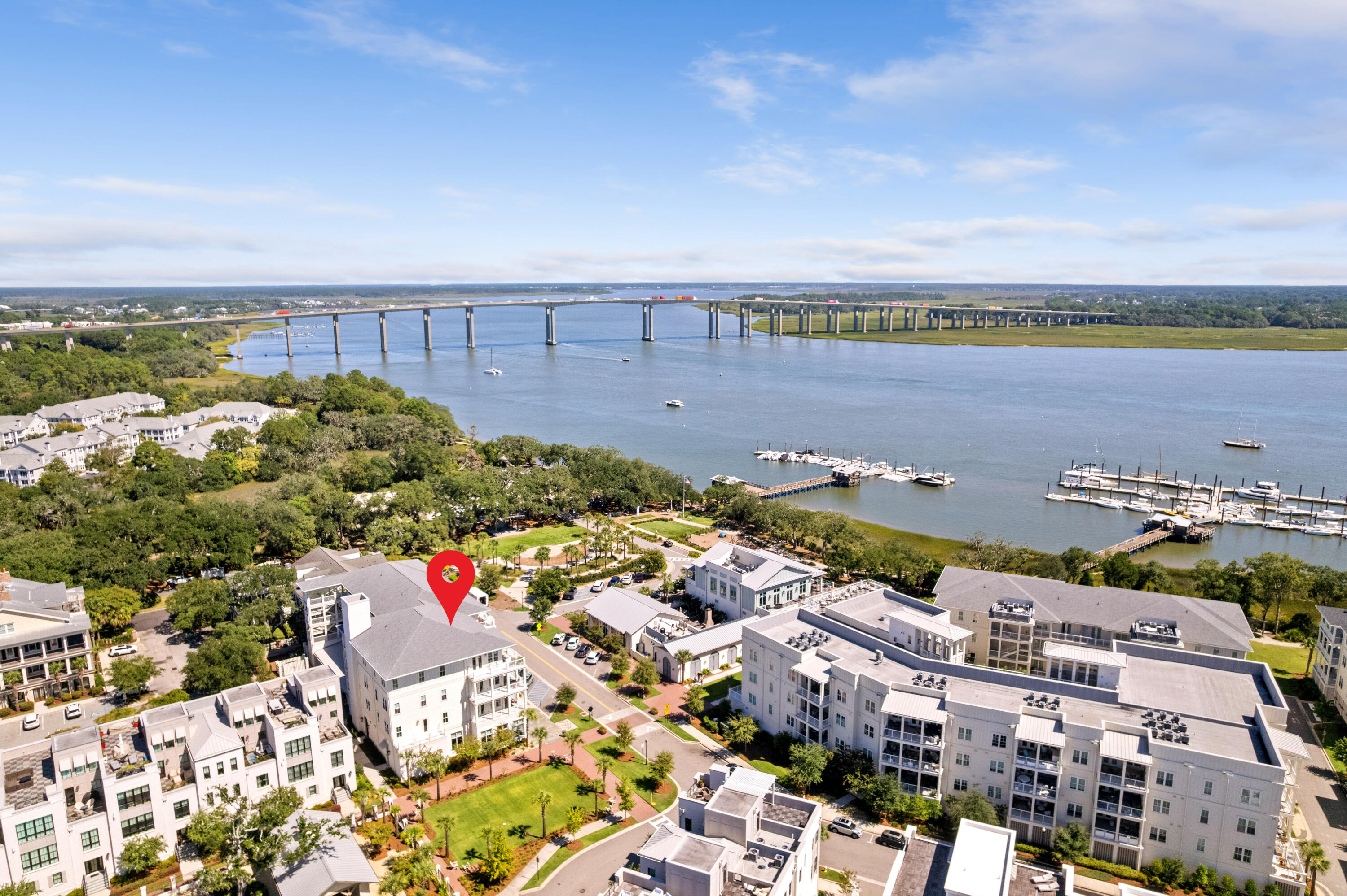 Aerial view of waterfront homes and marina, with a red pin marking a building beside the river.