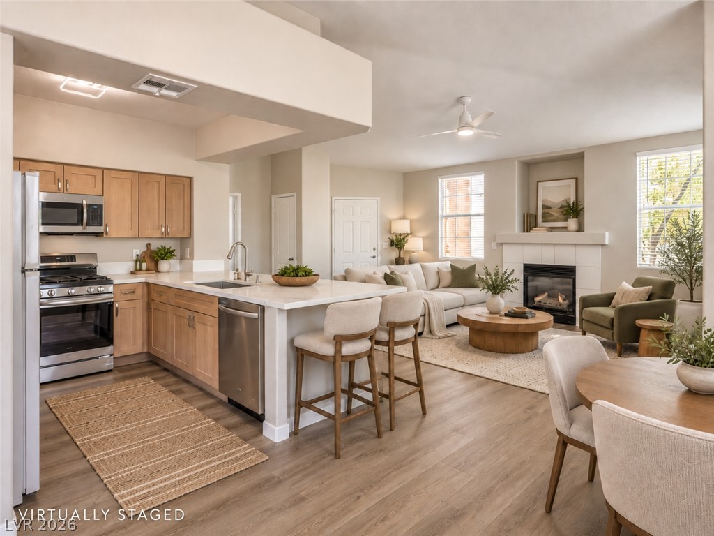 Open-plan kitchen and living room with a white island, bar stools, and a fireplace.