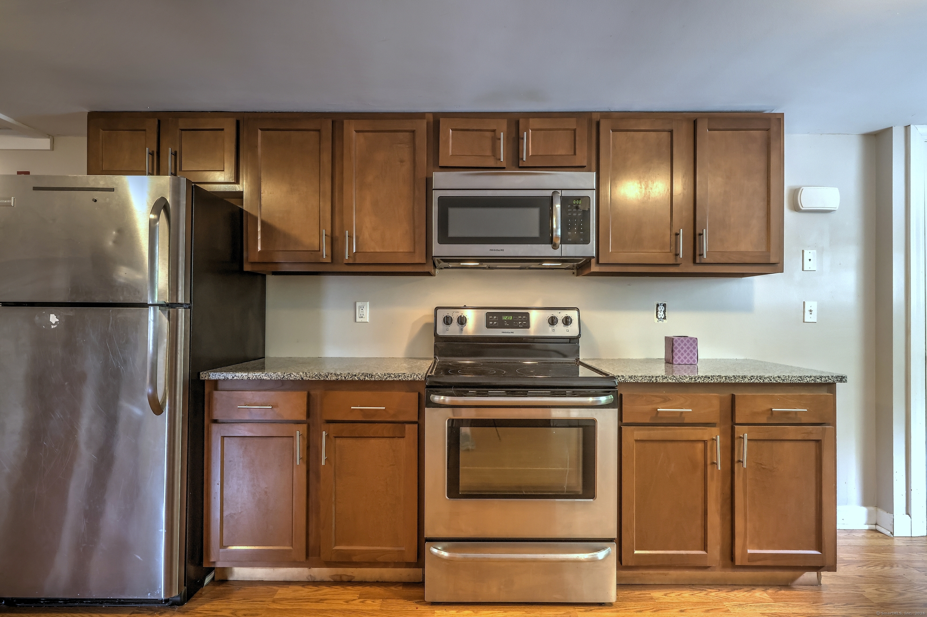 Kitchen with brown cabinets, stone counters, and stainless-steel appliances.