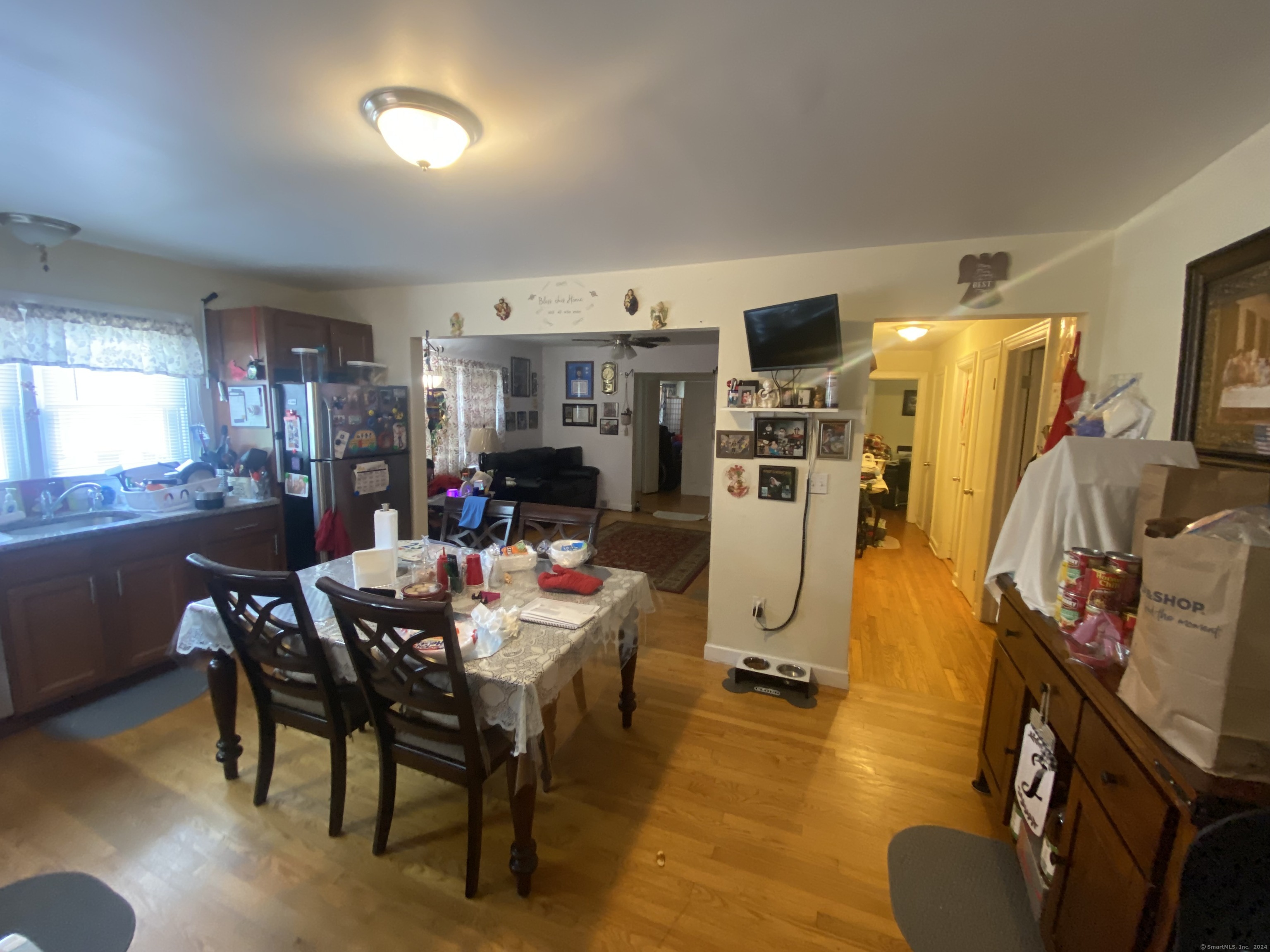 Dining area with a cluttered table beside the kitchen, opening into the living room and hallway.