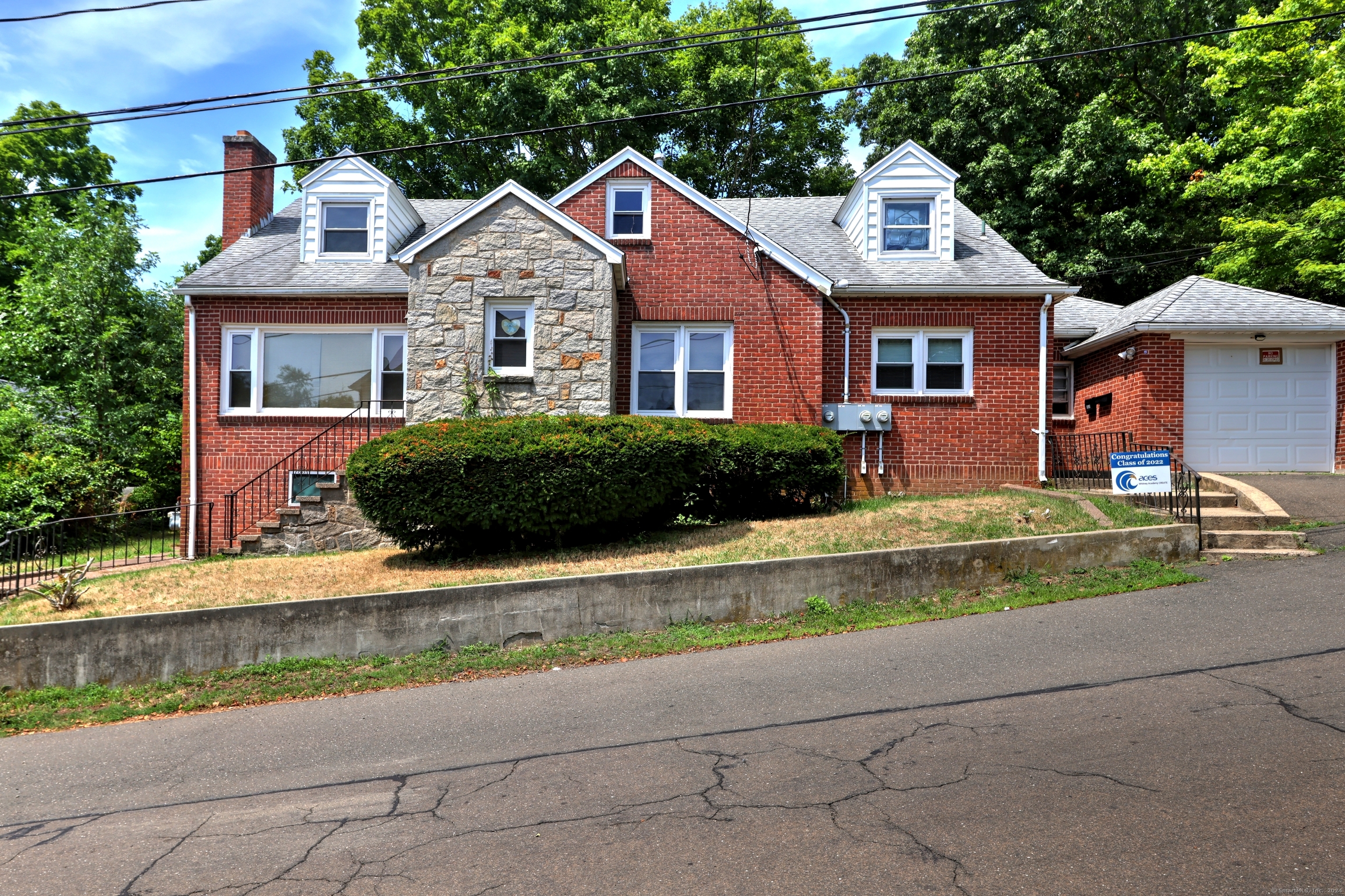 Red brick house with a stone facade, twin dormers, and an attached garage.