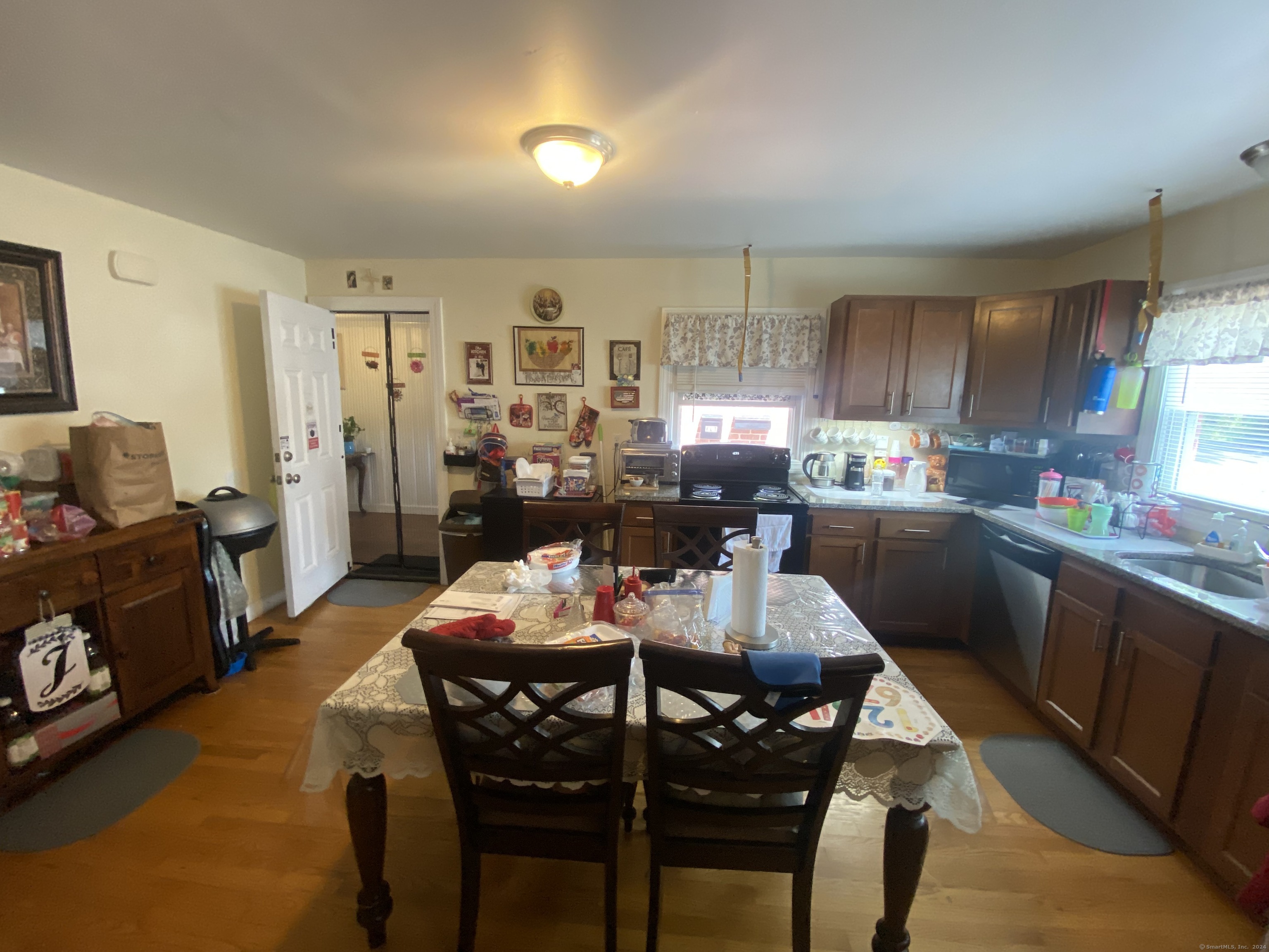 Kitchen with wood cabinets, a black electric stove, and a dining table in the foreground.