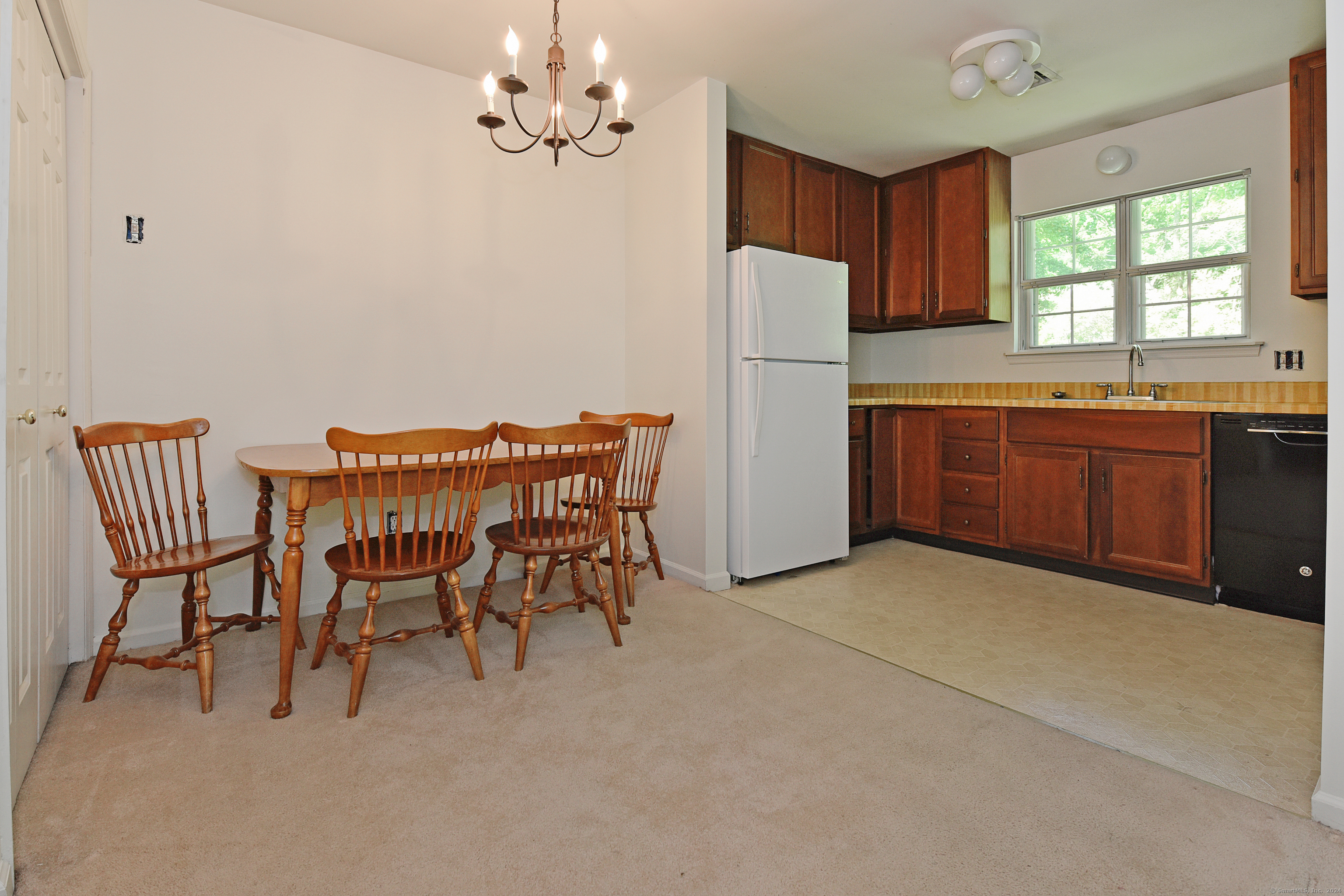Kitchen and dining area with dark wood cabinets, a white refrigerator, and a wooden table with chairs.