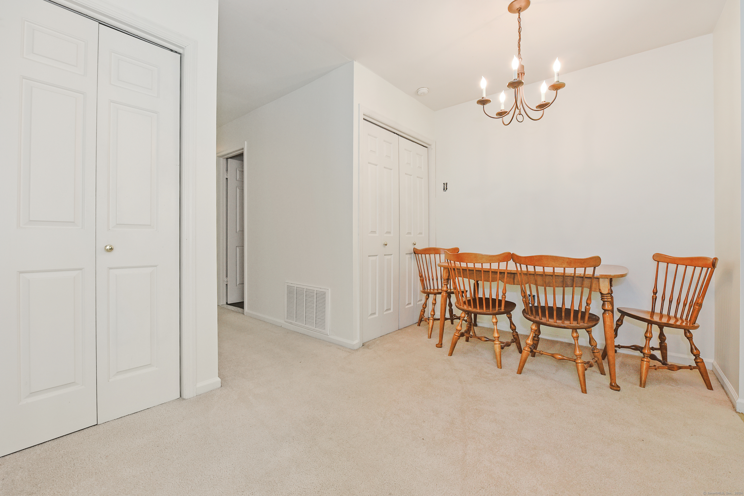Dining area with a wooden table and spindle-back chairs beneath a brass chandelier.
