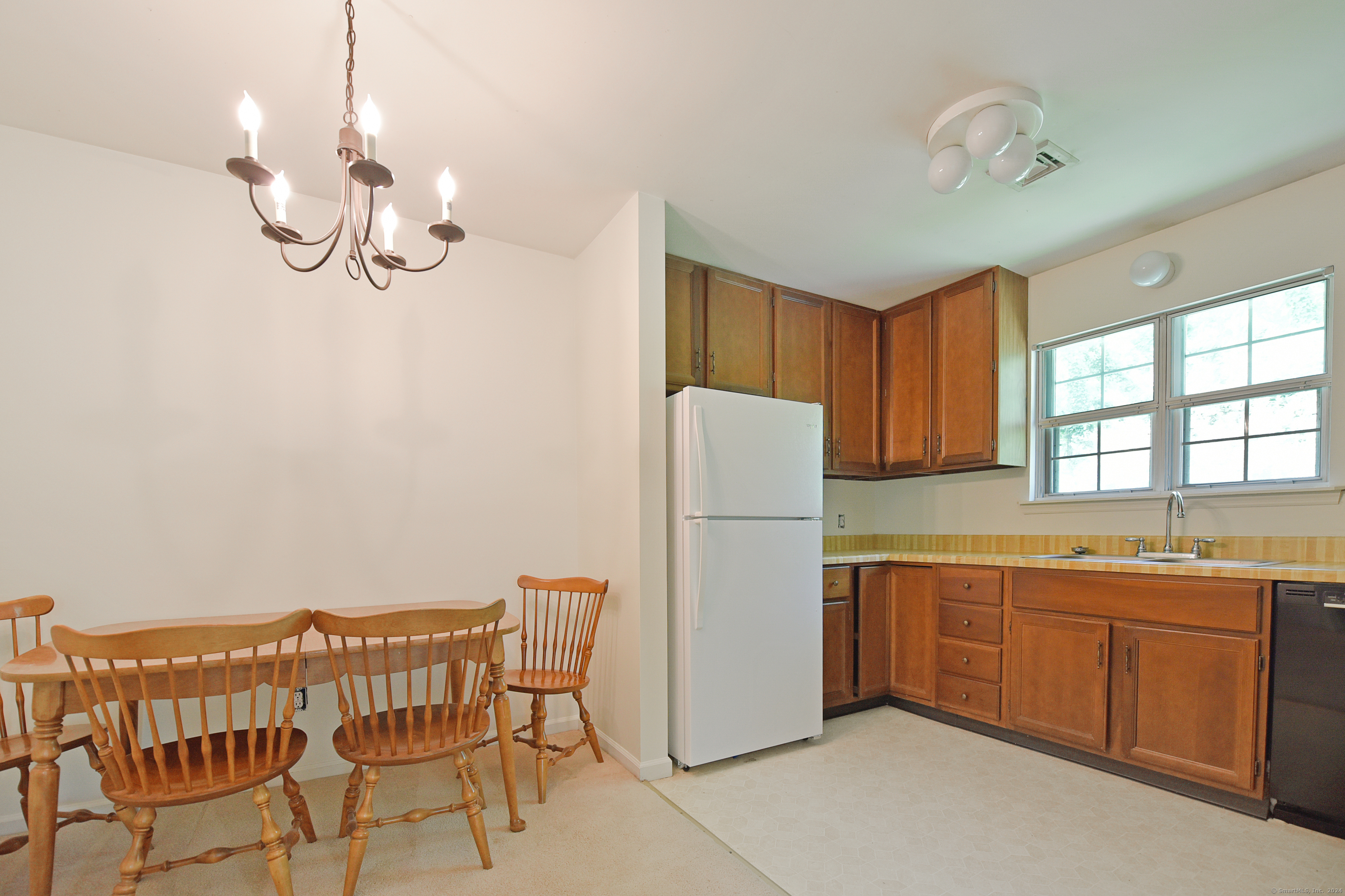 Kitchen and dining area with wood cabinets, a white refrigerator, and a wooden dining set.