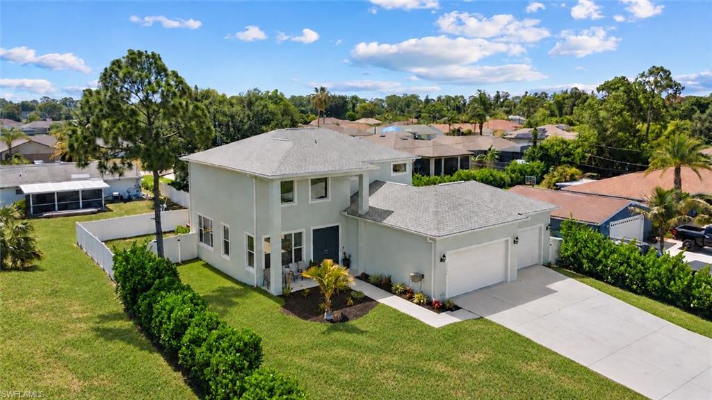 Aerial view of a gray two-story home with an attached garage and broad lawn.