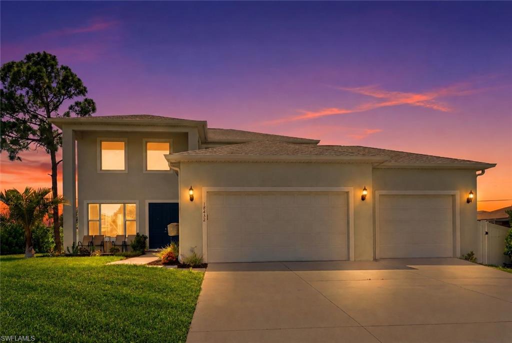 Two-story gray home with double and single garages at sunset.