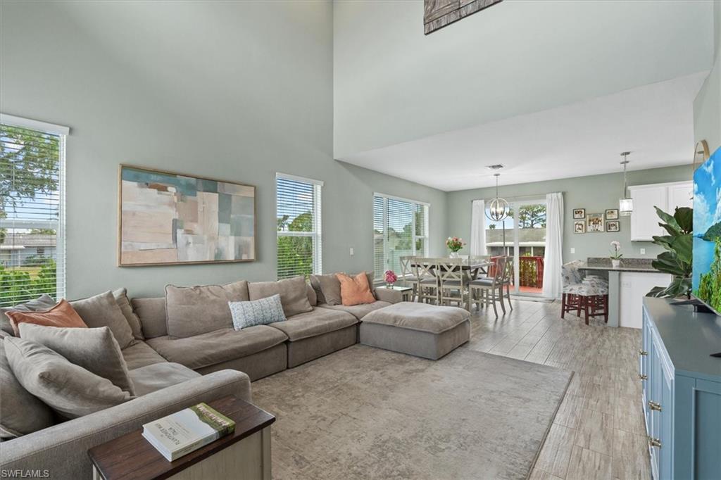 Open living room with a sectional sofa, high ceilings, and dining area beside the kitchen.