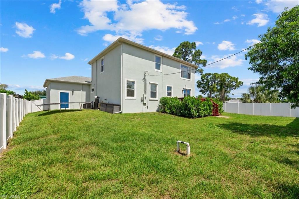 Two-story gray house with a fenced grassy backyard and a small deck.