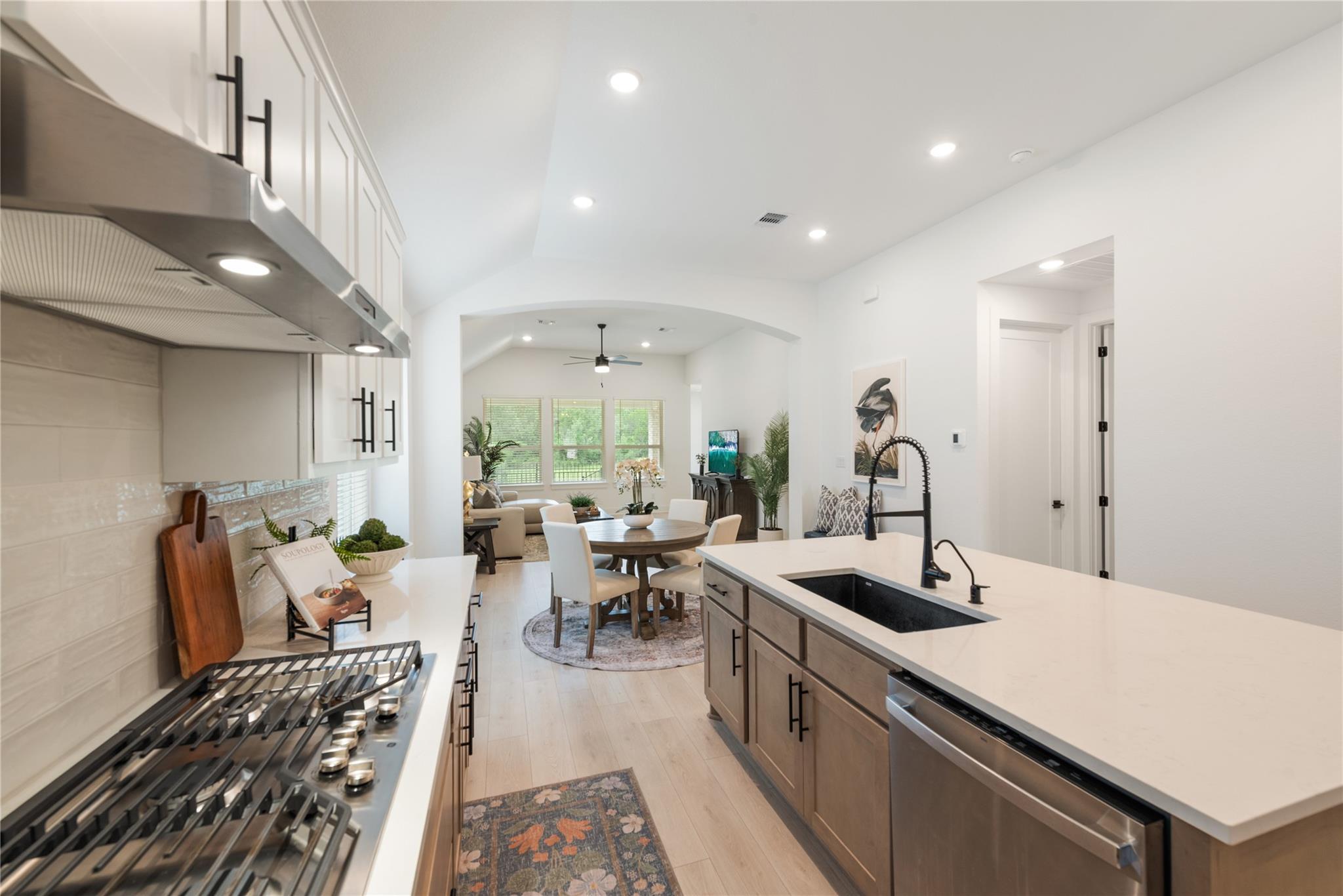Staged kitchen with a large island, gas range, and open dining and living areas.