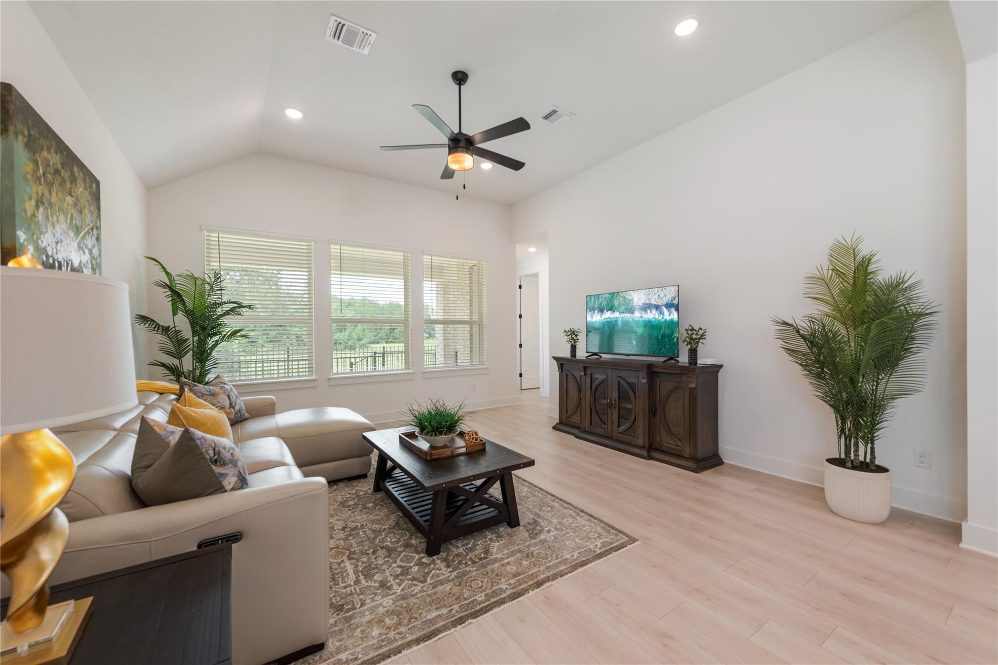 Living room with vaulted ceiling, three large windows, and a furnished seating area.