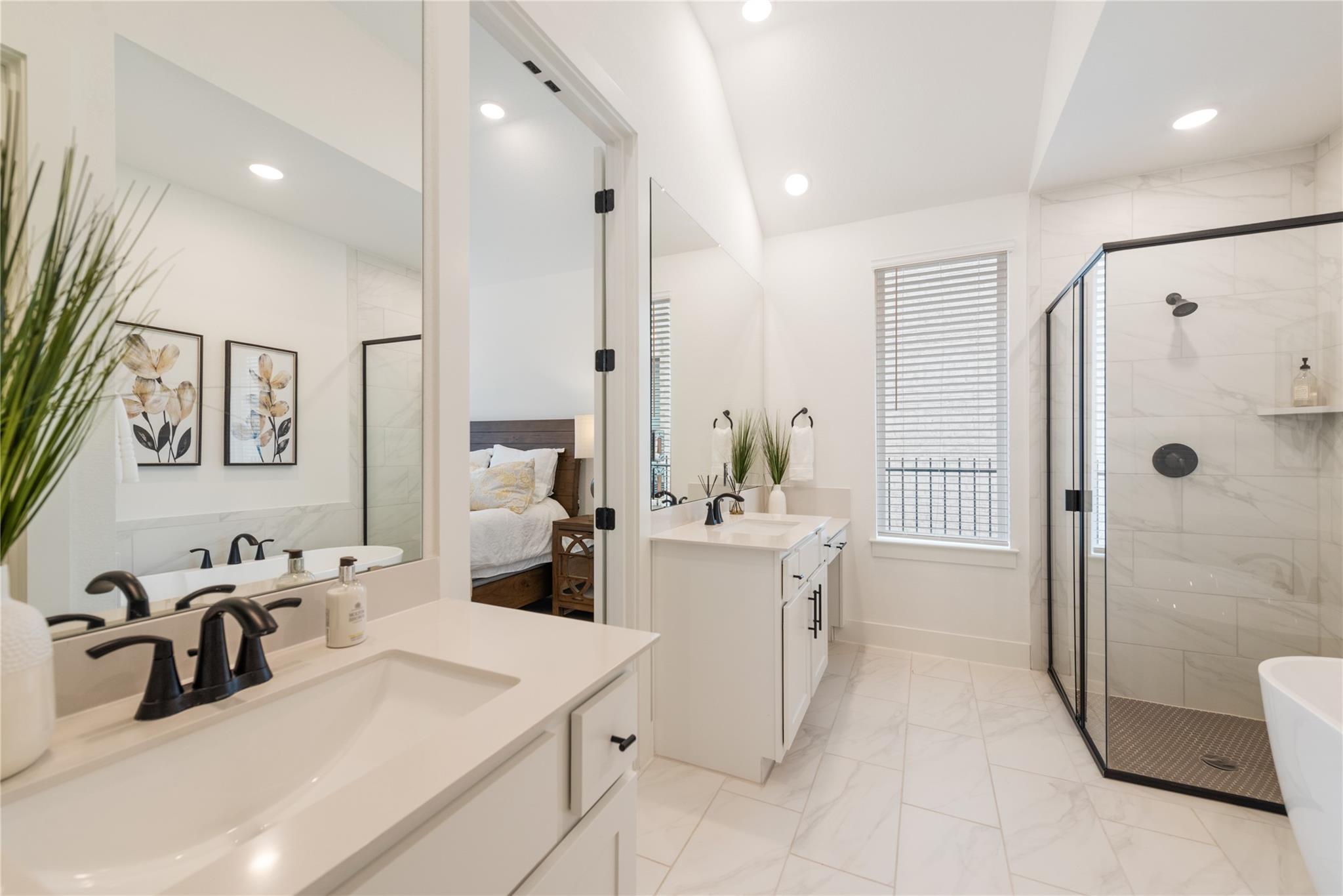 Bright primary bathroom with double vanities, a glass-enclosed shower, and a freestanding tub.