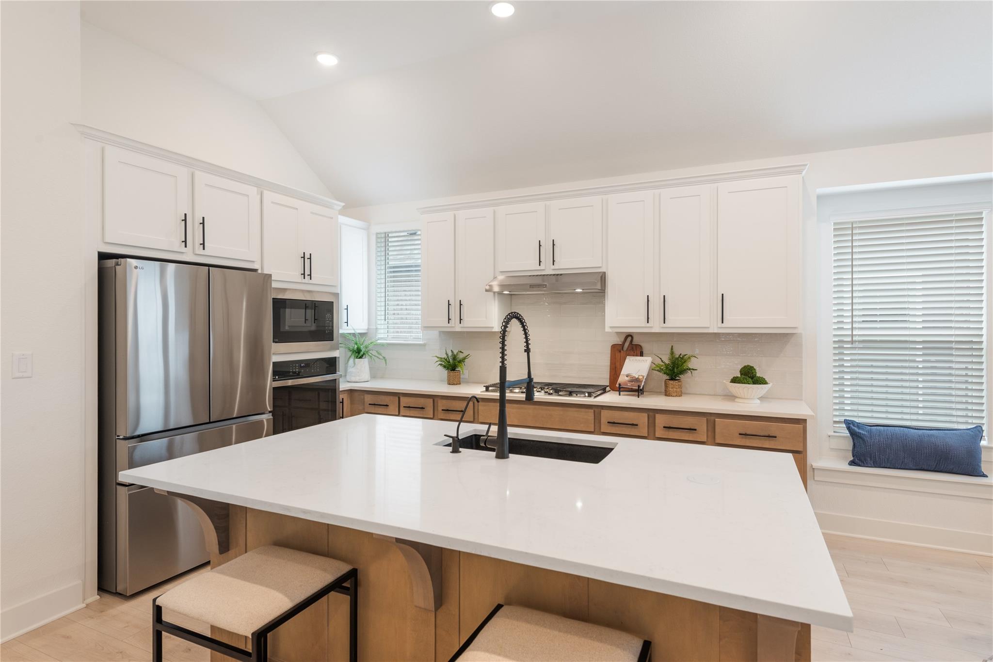 Bright kitchen with a large white island, white cabinets, and stainless steel appliances.